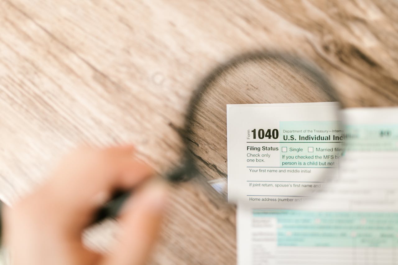 footer-cta Close-up image of IRS Form 1040 under a magnifying glass on a wooden surface.